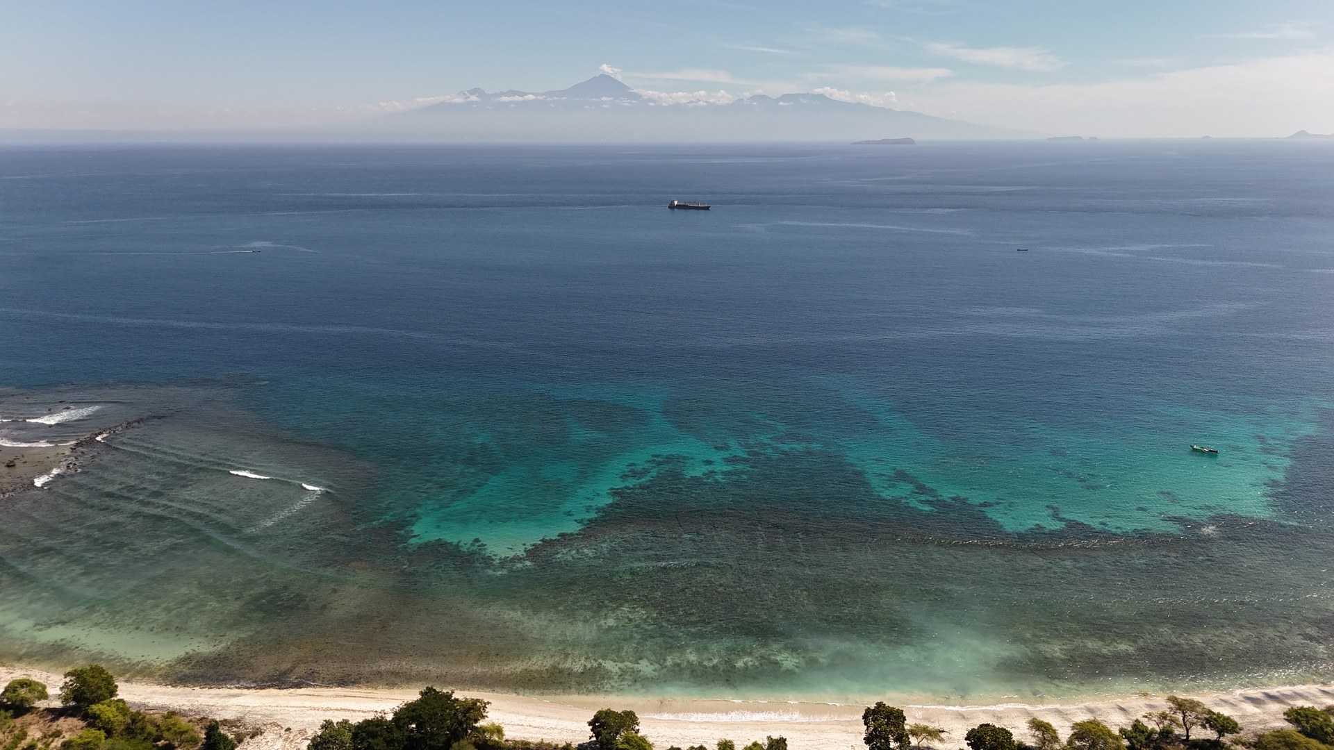 Reef break offshore with Lombok and Rinjani volcano in the distance